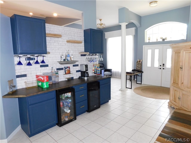 kitchen with blue cabinetry, wine cooler, butcher block countertops, and decorative columns