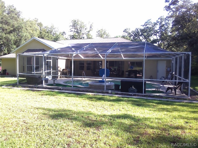 back of property featuring glass enclosure, a patio area, and a lawn