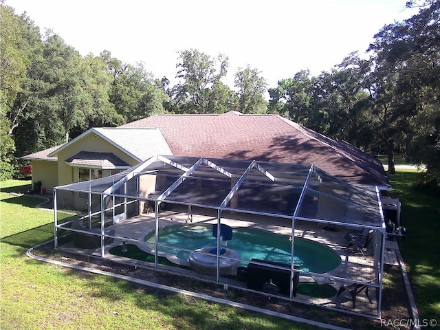 back of house featuring a lanai, a patio area, and a lawn