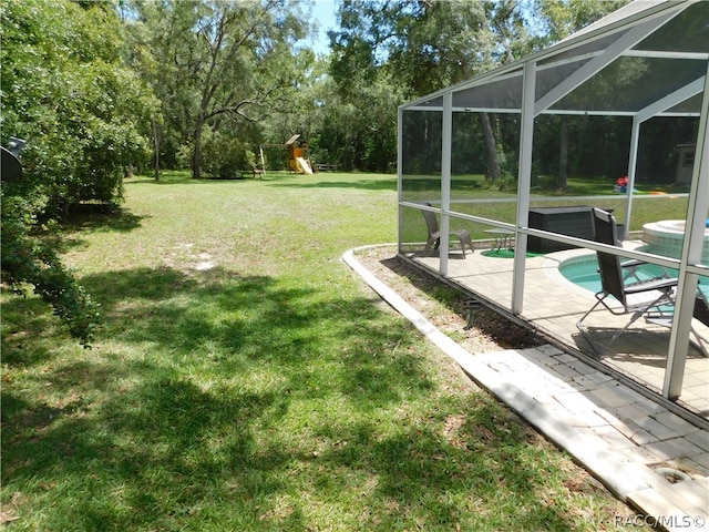 view of yard featuring glass enclosure, a patio area, and a playground