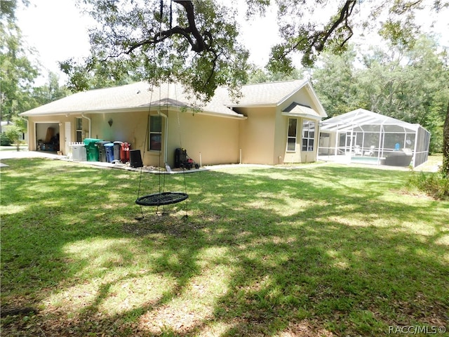 rear view of house featuring a lanai, a lawn, and a swimming pool