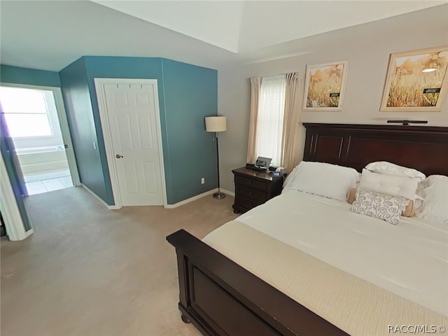 bedroom featuring ensuite bath and light colored carpet