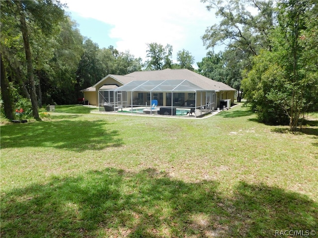 back of house featuring a lanai and a yard