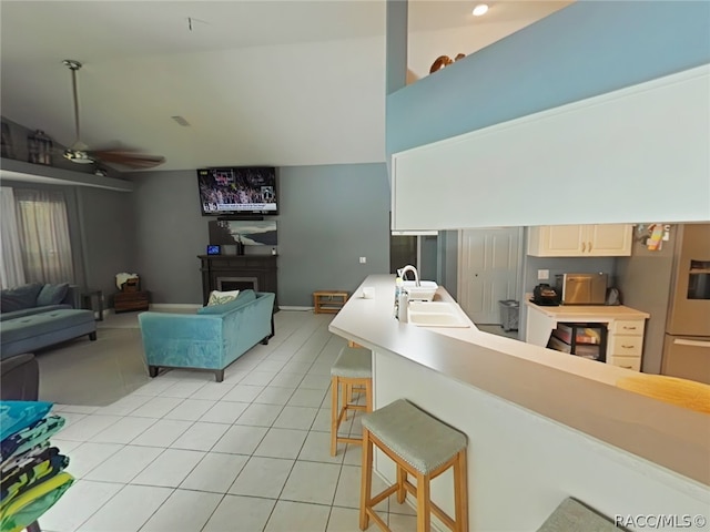 living room featuring light tile patterned floors, vaulted ceiling, ceiling fan, and sink