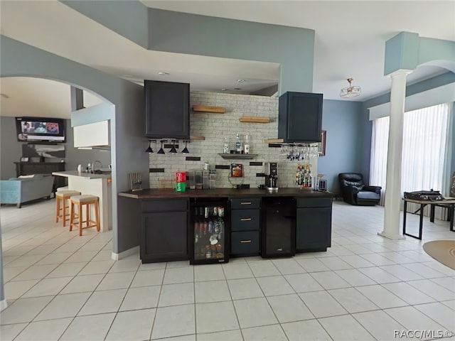 kitchen with light tile patterned floors, tasteful backsplash, wine cooler, and ornate columns