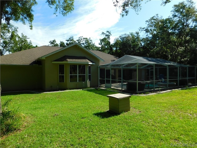 back of house featuring a lawn, glass enclosure, and a swimming pool