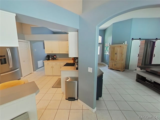 kitchen with white cabinets, stainless steel fridge, and light tile patterned floors