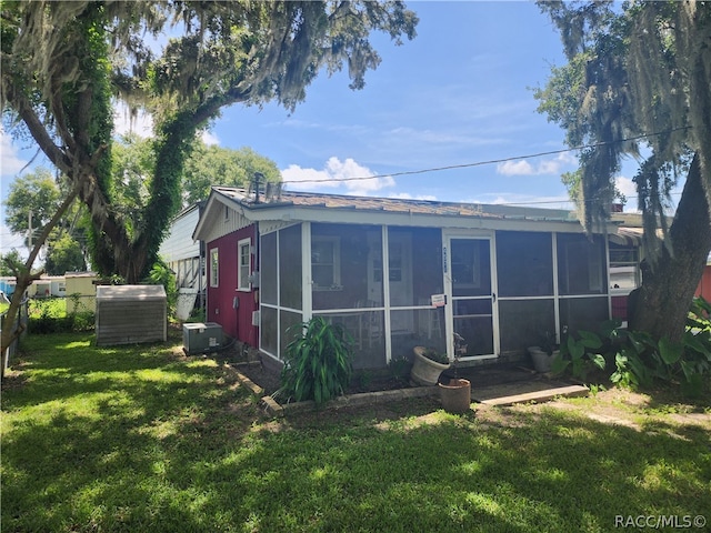 view of outbuilding with a sunroom and a lawn