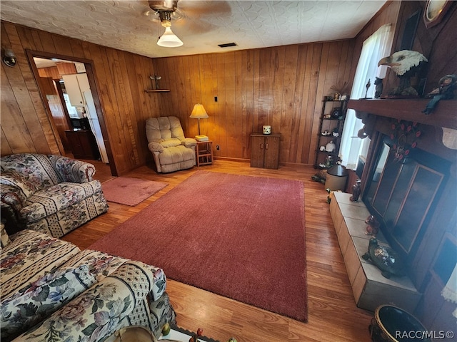 living room featuring wood walls, ceiling fan, and wood-type flooring