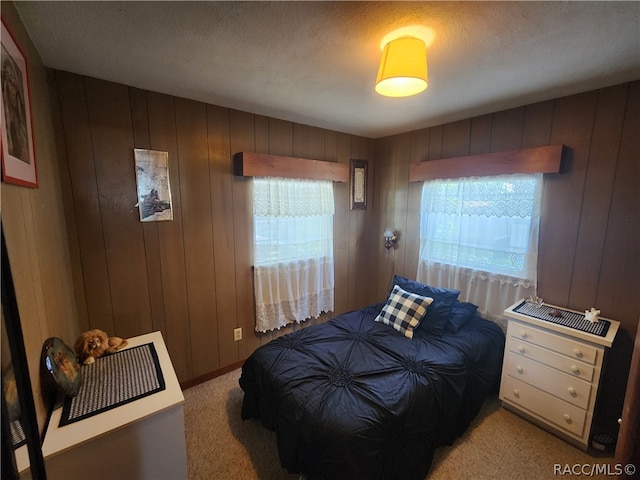 carpeted bedroom with a textured ceiling and wood walls