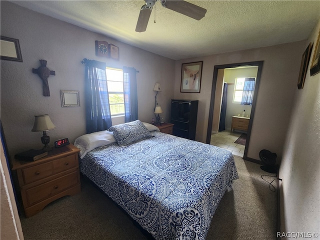 carpeted bedroom with ensuite bathroom, ceiling fan, and a textured ceiling