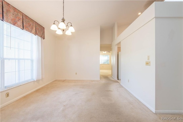 carpeted spare room with a chandelier