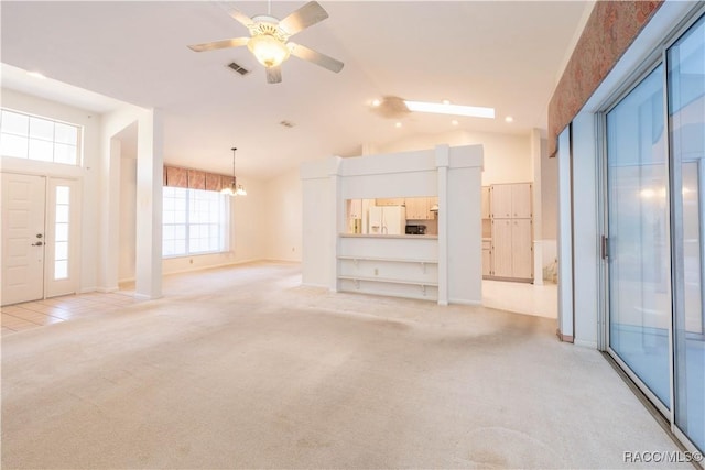 unfurnished living room with lofted ceiling, ceiling fan with notable chandelier, and light carpet