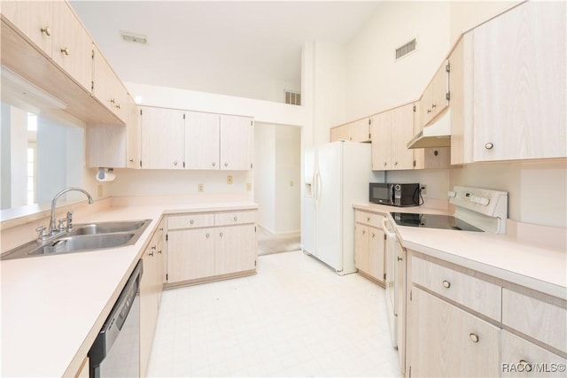 kitchen featuring light brown cabinetry, sink, white appliances, and a high ceiling