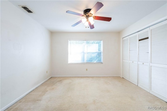 unfurnished bedroom with light colored carpet, a closet, and ceiling fan