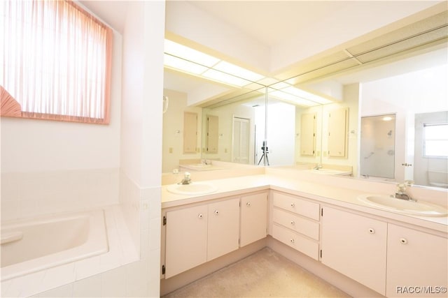 bathroom with vanity and tiled tub