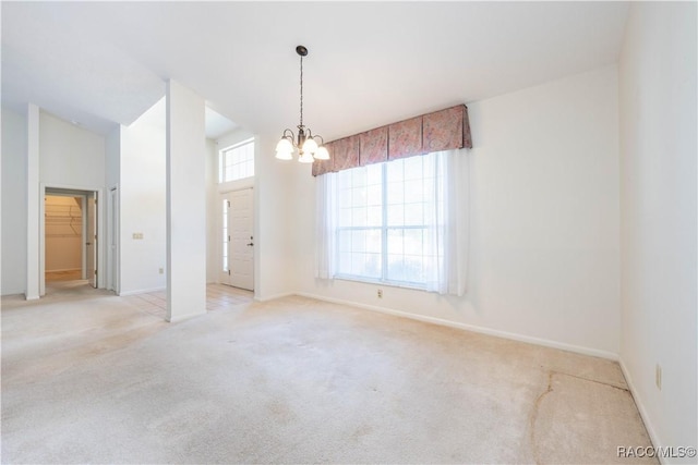 spare room with light carpet and a notable chandelier