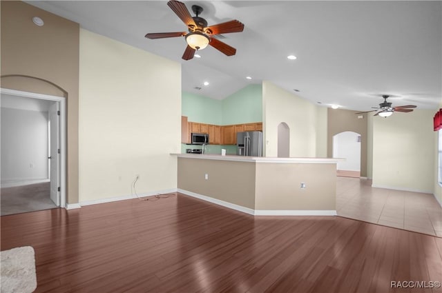 unfurnished living room with light hardwood / wood-style floors, high vaulted ceiling, and ceiling fan