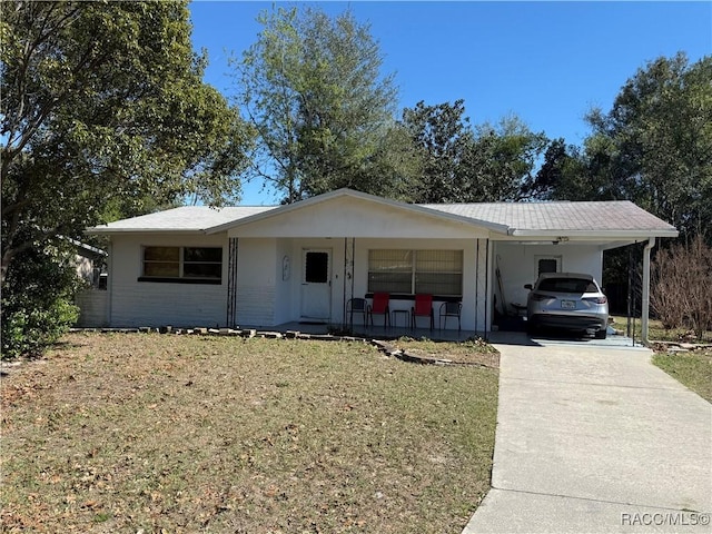 ranch-style home featuring covered porch, a carport, and a front yard