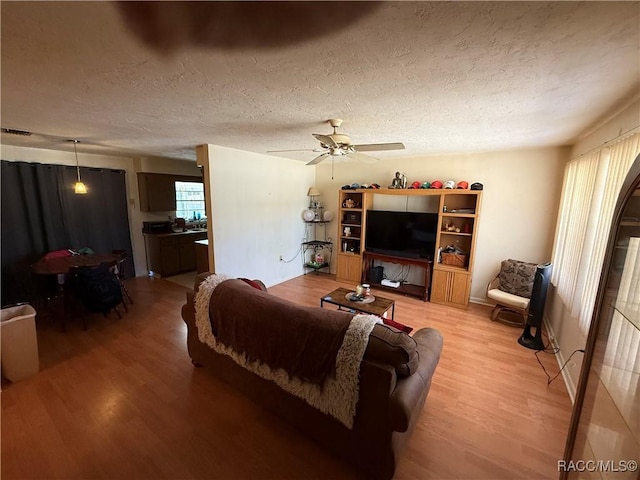 living room featuring a textured ceiling, hardwood / wood-style flooring, and ceiling fan