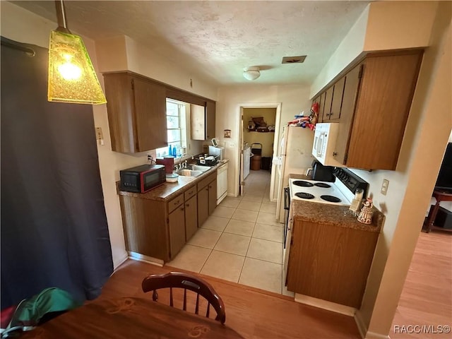 kitchen featuring hanging light fixtures, white appliances, a textured ceiling, light tile patterned floors, and sink