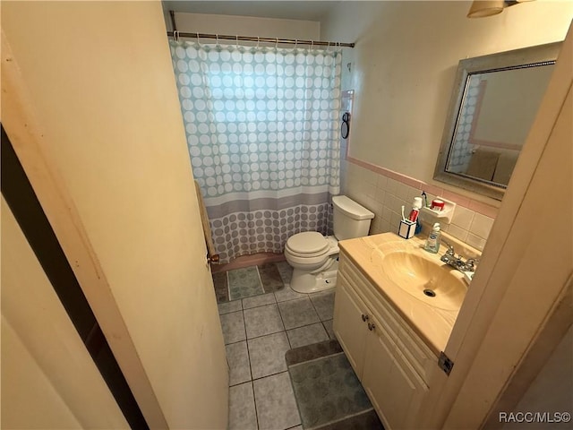 bathroom with tile patterned flooring, toilet, tile walls, curtained shower, and vanity