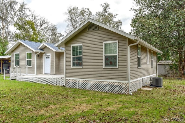 rear view of property with central AC and a lawn