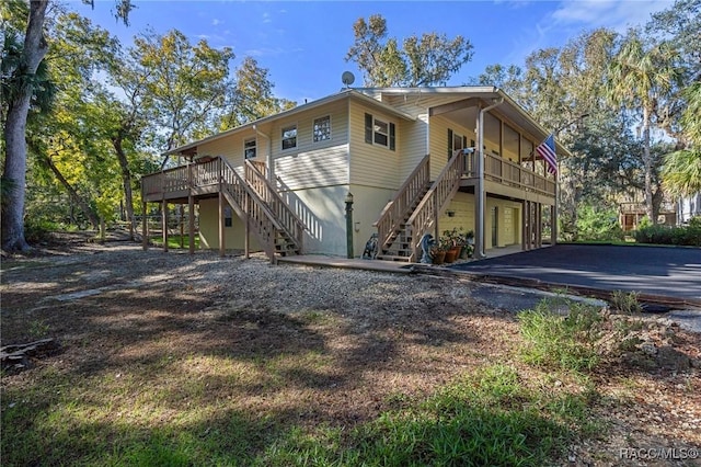 view of front facade with driveway, stairs, and a wooden deck