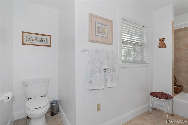 bathroom featuring toilet, a bathing tub, and baseboards