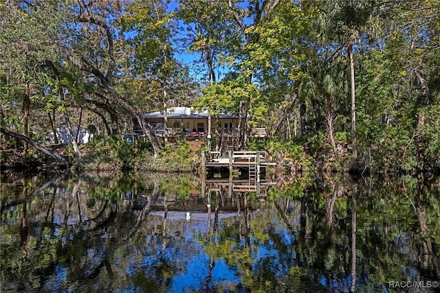 back of property featuring a water view, stairs, and a view of trees