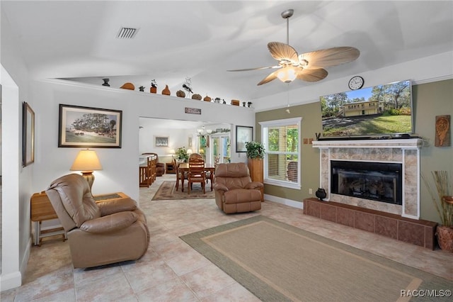 living area with ceiling fan, a tile fireplace, visible vents, baseboards, and vaulted ceiling