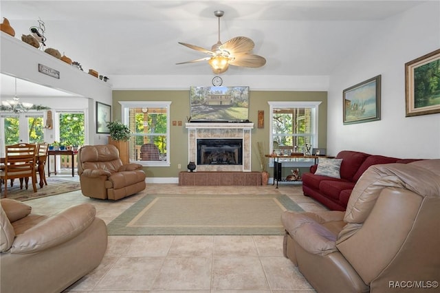 tiled living room featuring a tile fireplace, ceiling fan with notable chandelier, vaulted ceiling, and a wealth of natural light