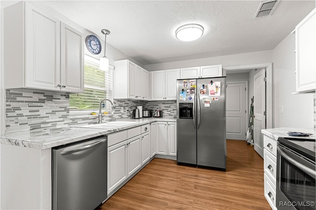 4325 NE 33rd Ave, Ocala, FL 34479 - kitchen with stainless steel appliances, white cabinets, tasteful backsplash, light wood-style floors, and a textured ceiling