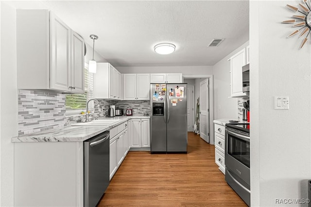 4325 NE 33rd Ave, Ocala, FL 34479 - kitchen featuring appliances with stainless steel finishes, light wood-type flooring, tasteful backsplash, white cabinets, and a textured ceiling