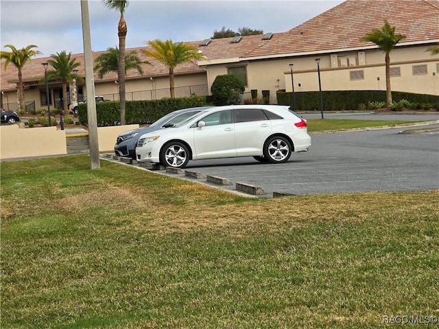 view of parking / parking lot featuring a yard