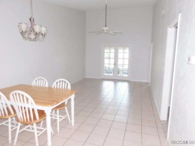 dining area featuring ceiling fan with notable chandelier, light tile patterned floors, high vaulted ceiling, and french doors