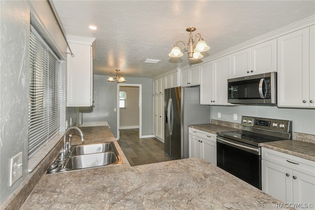 kitchen featuring white cabinetry, sink, pendant lighting, and appliances with stainless steel finishes