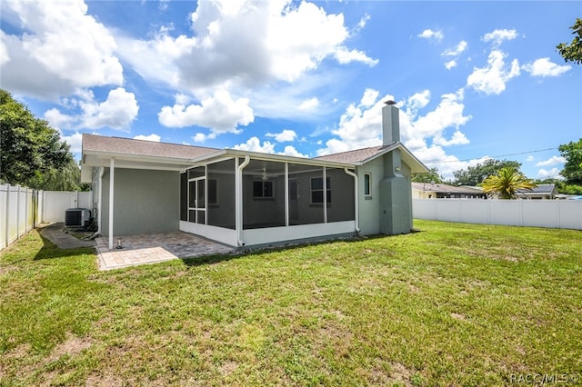 rear view of property featuring a sunroom, central AC, a patio area, and a lawn