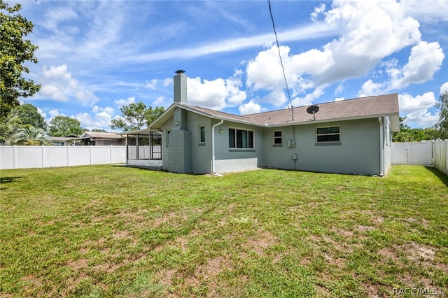 rear view of property featuring a lawn and a sunroom