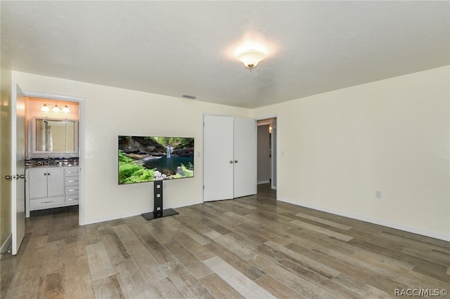 bedroom with hardwood / wood-style flooring, ensuite bathroom, and sink