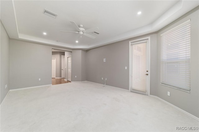 empty room with a raised ceiling, baseboards, a ceiling fan, recessed lighting, and light colored carpet