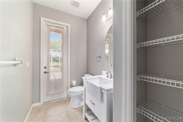 bathroom featuring toilet, visible vents, baseboards, tile patterned flooring, and vanity
