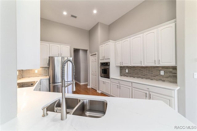 kitchen with backsplash, white cabinets, visible vents, and appliances with stainless steel finishes