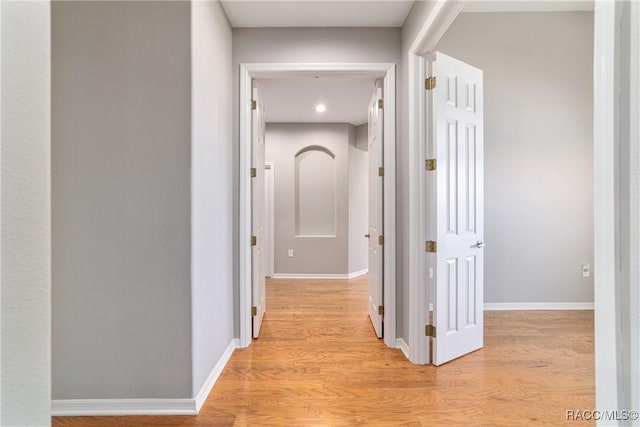 corridor featuring light wood-type flooring and baseboards