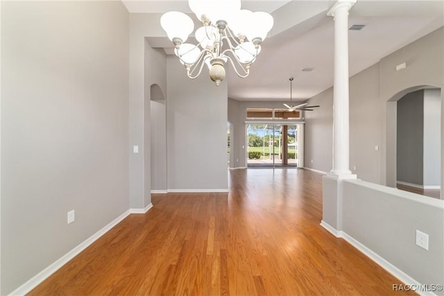 unfurnished dining area with light wood-style floors, baseboards, ornate columns, and arched walkways
