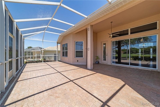 view of patio with ceiling fan and glass enclosure