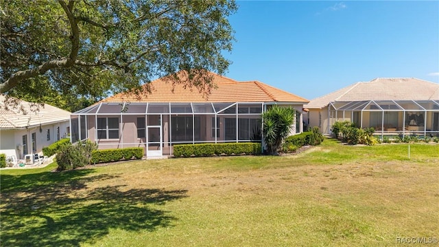 rear view of house featuring a lawn, a lanai, and a tiled roof