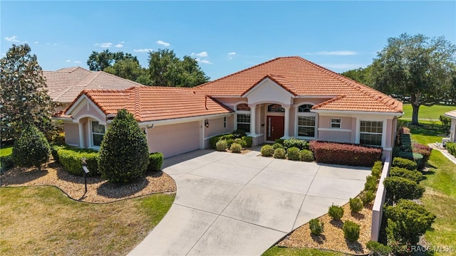mediterranean / spanish-style home featuring a tiled roof, a garage, driveway, stucco siding, and a front lawn