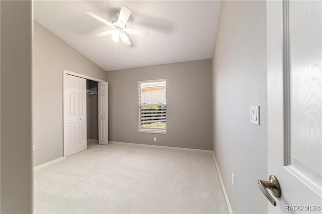 unfurnished bedroom with vaulted ceiling, light carpet, baseboards, a closet, and a ceiling fan