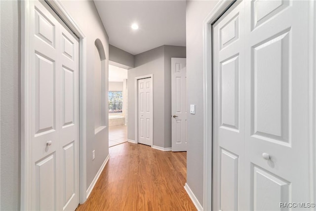 hall featuring light wood finished floors, baseboards, and recessed lighting